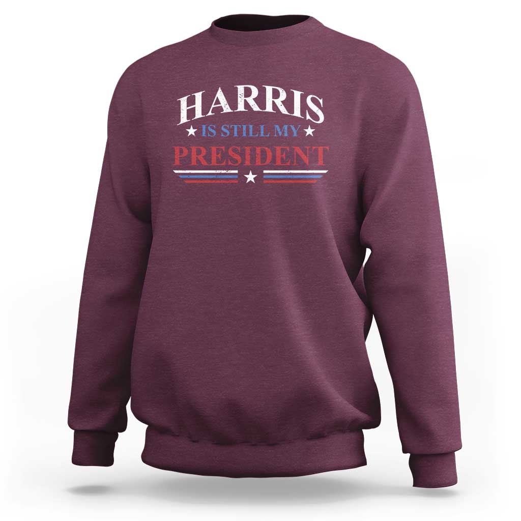 Maroon crewneck sweatshirt with Harris "Still My President" star-striped graphic