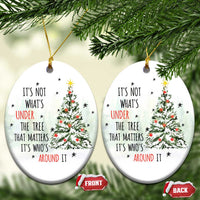 Two white oval Christmas ornaments with tree and quote, hanging from gold strings