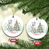 Two white circular Christmas ornaments with tree and quote, hanging from gold strings