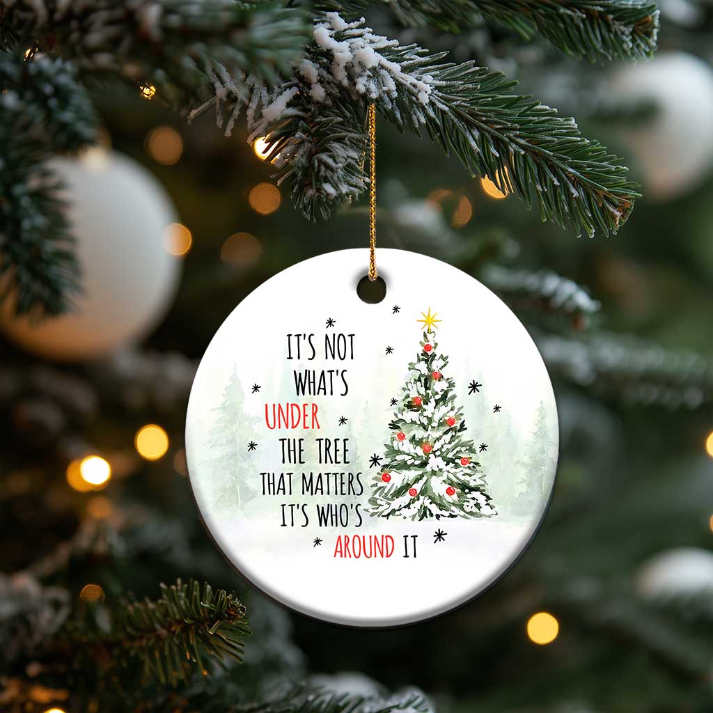 White circular Christmas ornament with tree and quote, hanging from a Christmas tree