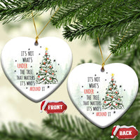 Two white heart-shaped Christmas ornaments with tree and quote, hanging by gold strings