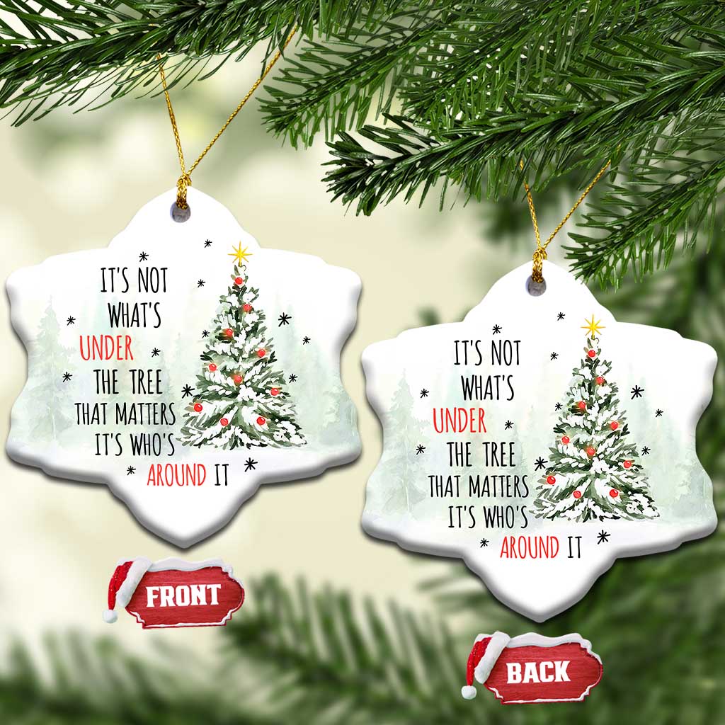 Two white heart-shaped Christmas ornaments with tree and quote, hanging on evergreen branches