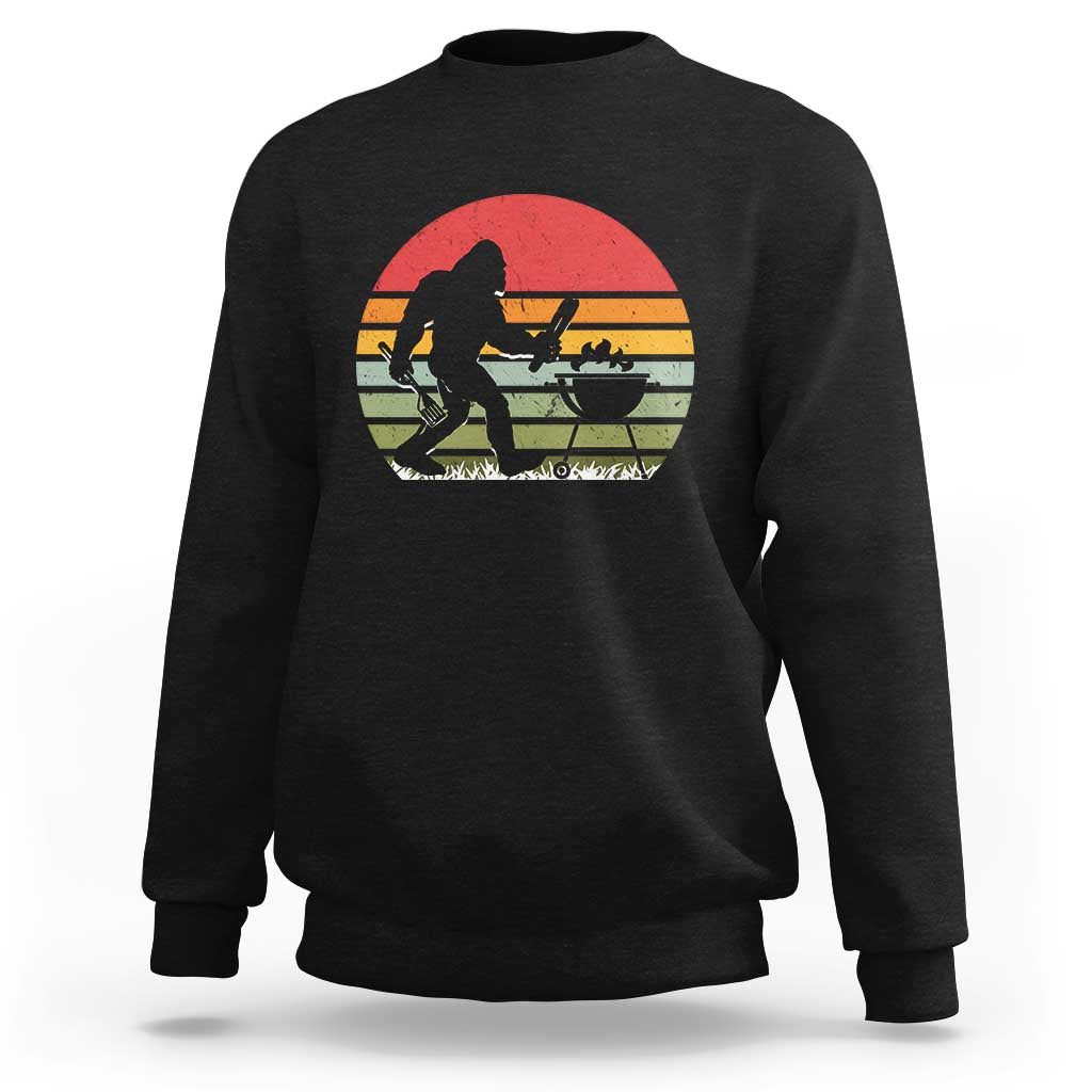 Black crewneck sweatshirt with Bigfoot BBQ chef graphic in red sunset circle