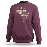 Maroon crewneck sweatshirt with 'Education Is Freedom' books graphic at center front