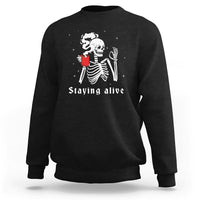Black crewneck sweatshirt with skeleton holding cup and 'Staying alive' graphic