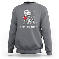 Charcoal gray crewneck sweatshirt with skeleton holding cup and 'Staying alive' graphic