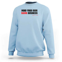 Light blue sweatshirt with “MIND YOUR OWN DAMN BUSINESS” graphic on chest