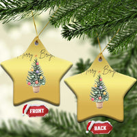 Two gold star-shaped Christmas ornaments with “Merry Bright” and decorated tree