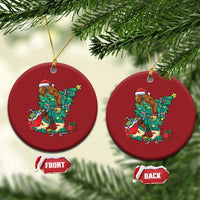 Pair of red round holiday ornaments with cartoon Bigfoot Santa decorating a Christmas tree.