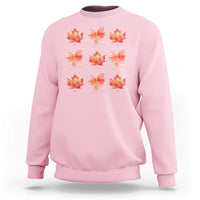 Light pink crewneck sweatshirt with orange bow and maple leaf graphic print.