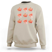 Sand beige crewneck sweatshirt with orange bow and maple leaf graphic print.