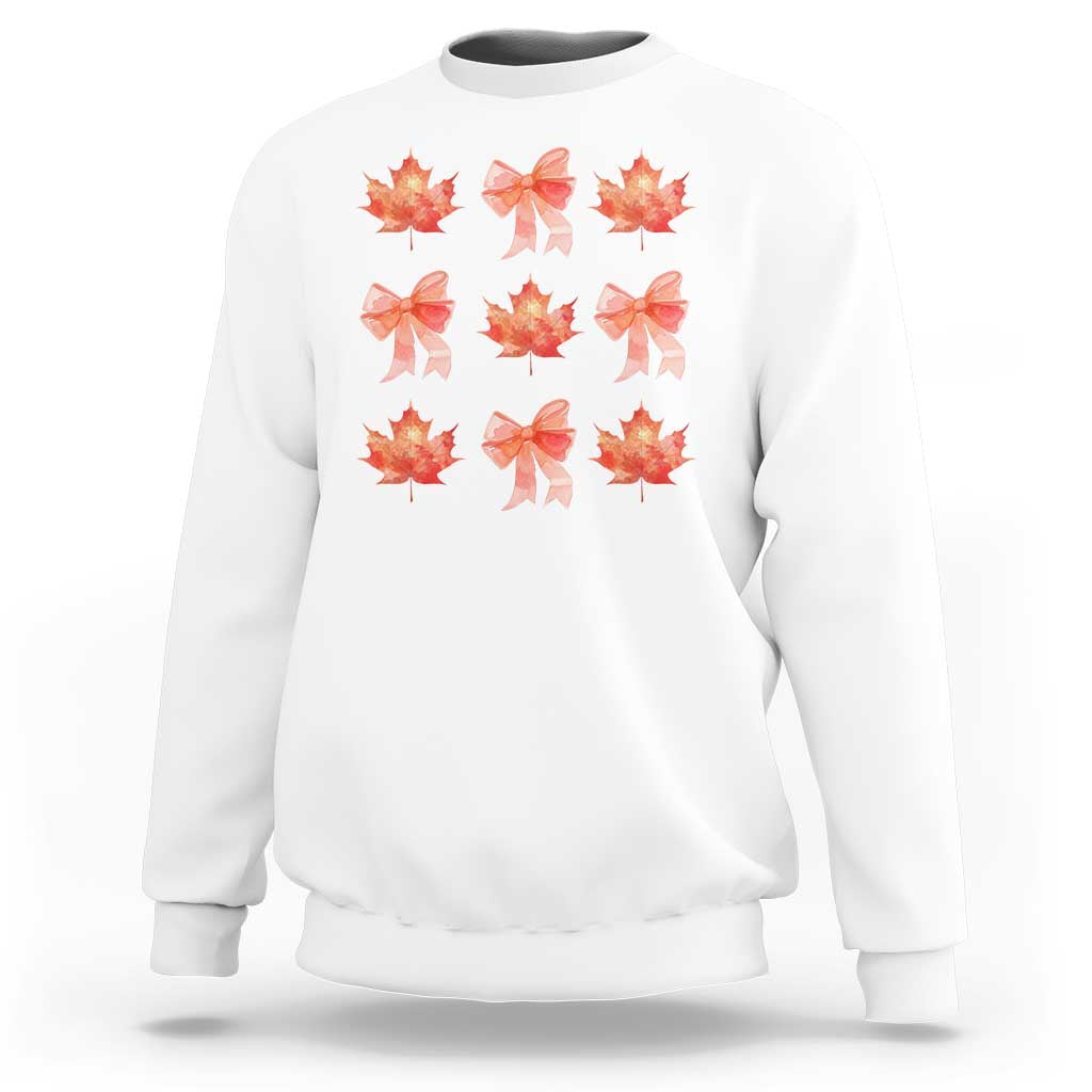 White crewneck sweatshirt with orange bow and maple leaf graphic print.