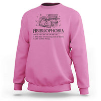 Pink crewneck sweatshirt with book-and-butterfly graphic and bold text design