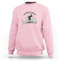 Light pink sweatshirt with open book and flower graphic plus 'Reading is magical' text