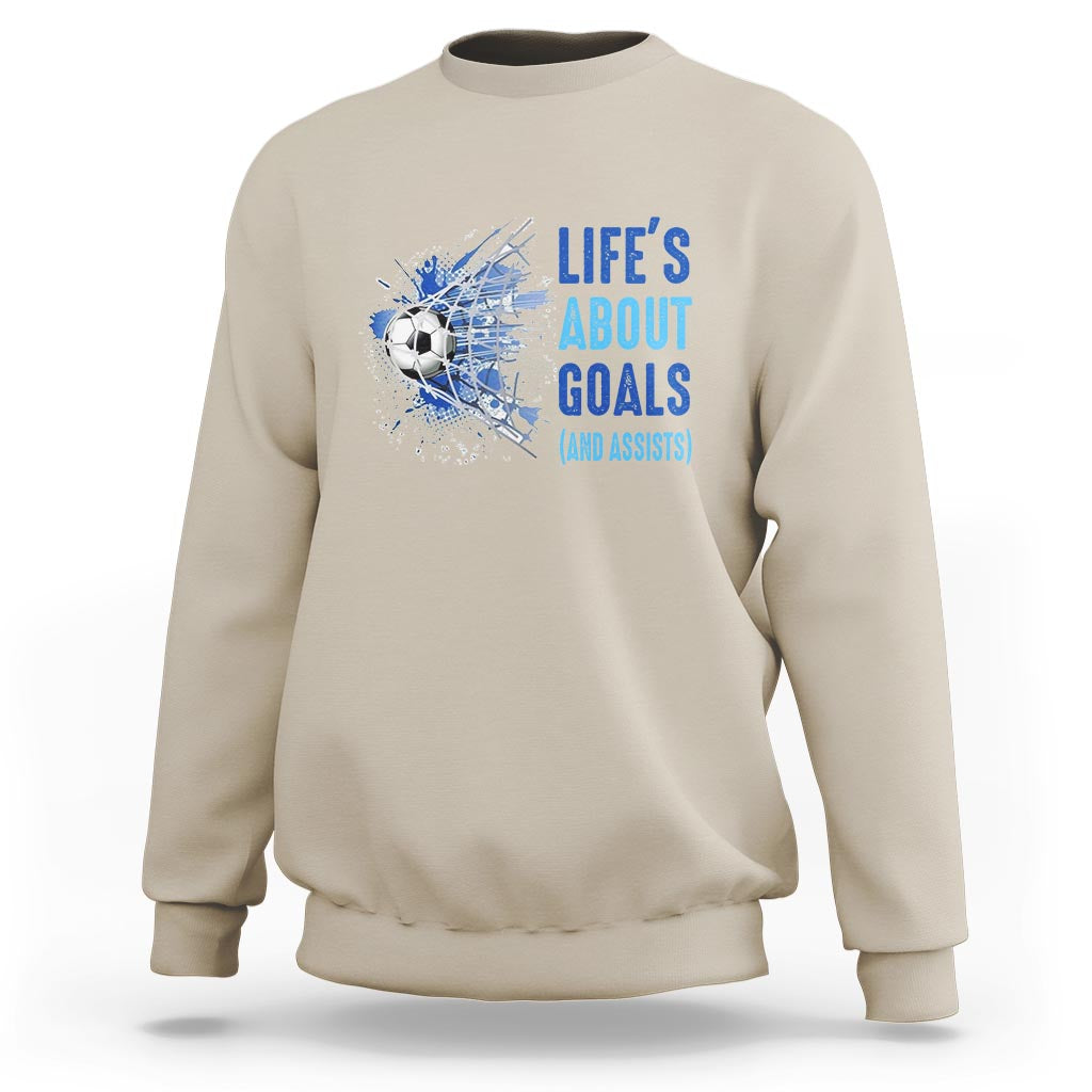 Sand soccer sweatshirt with blue “Life’s About Goals (and Assists)” graphic on chest