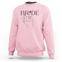 Light pink bride sweatshirt with “BRIDE” print and hand ring graphic on chest