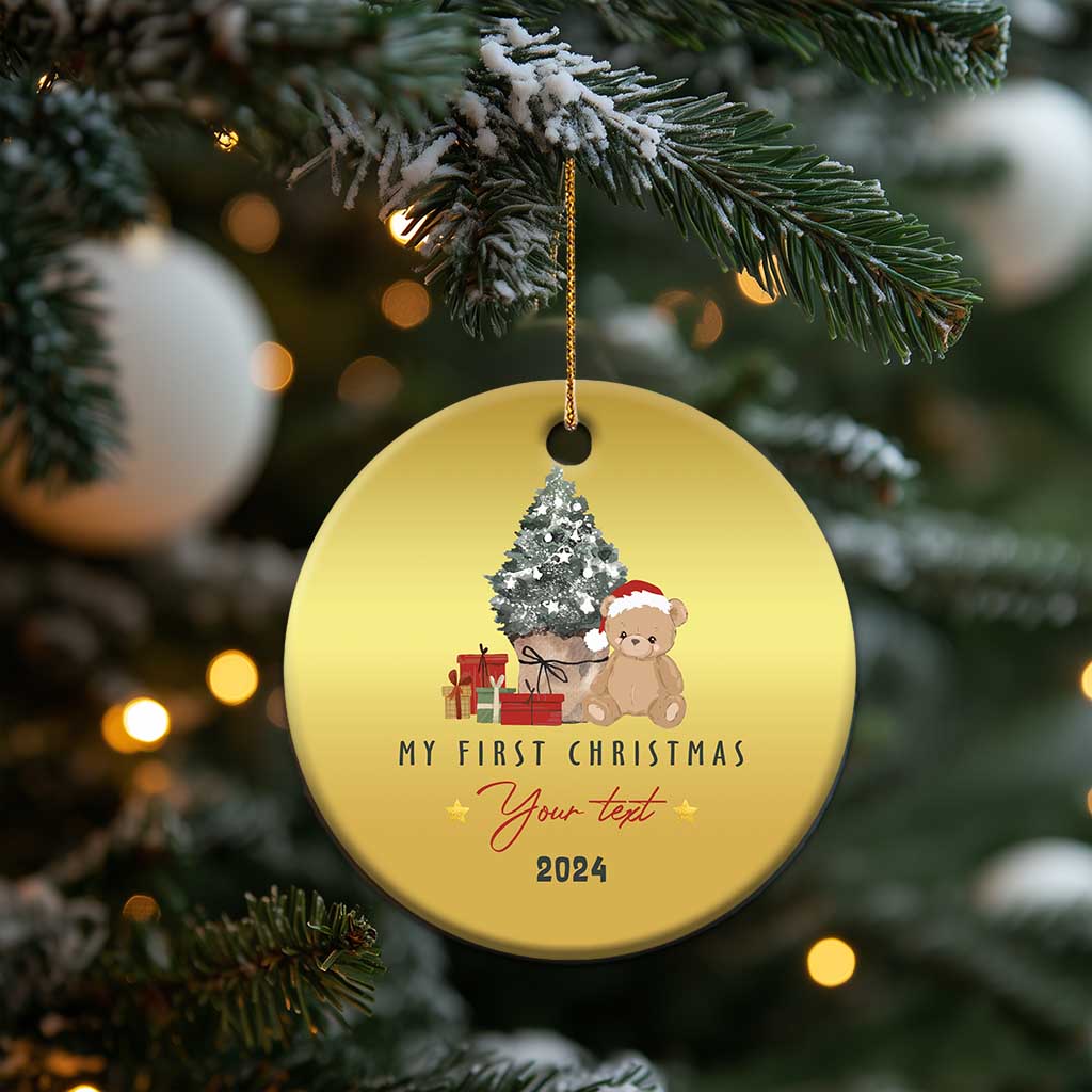 Gold round Christmas ornament on tree, with teddy, tree, “My First Christmas” and 2024