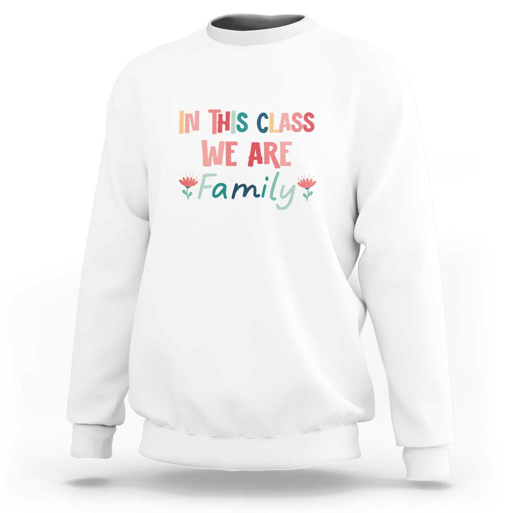 White crewneck sweatshirt with colorful 'In this class we are family' floral graphic.