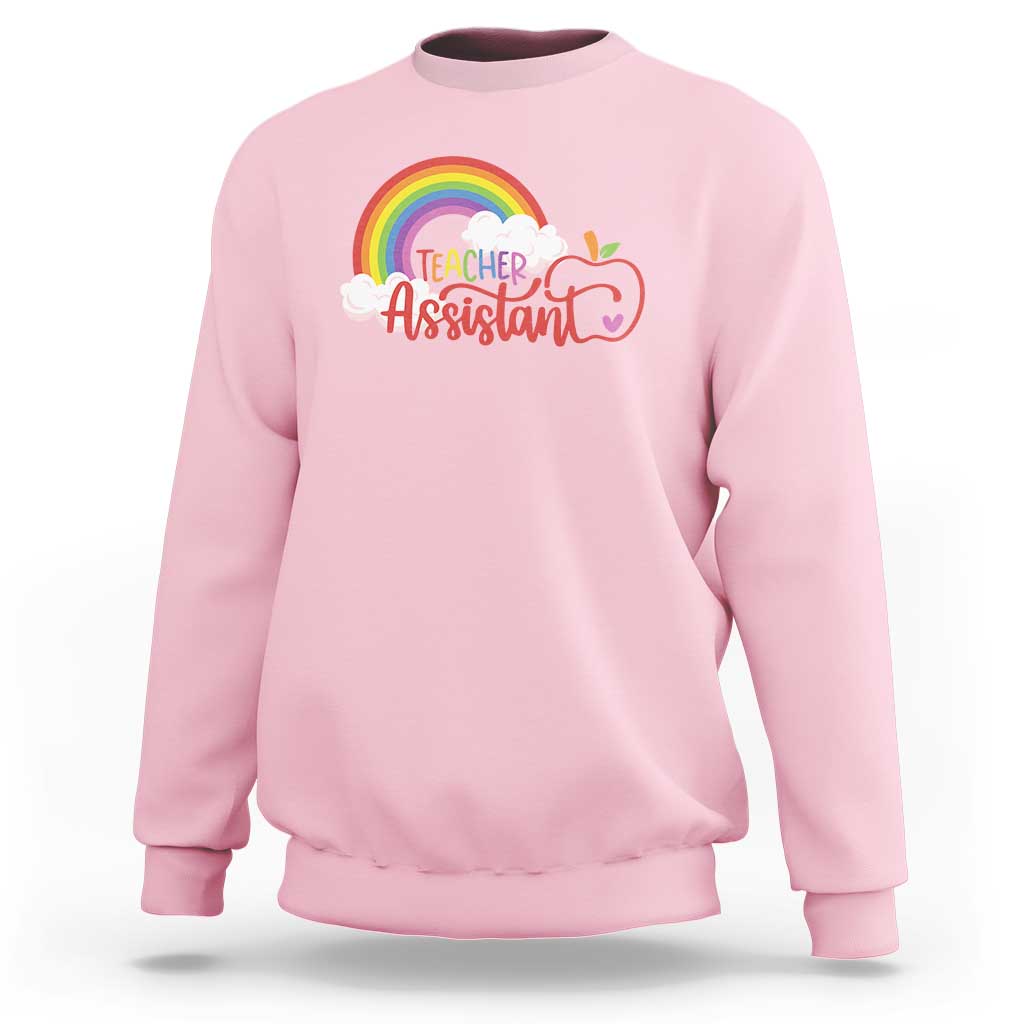 Light pink teacher assistant sweatshirt with rainbow cloud apple graphic on front.