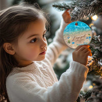Personalized engagement Christmas ornament on a tree, small round blue beach design with “Engaged”.