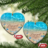 Personalized engagement Christmas ornament pair, heart shapes with blue ocean beach and “Engaged”.