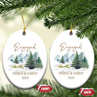 Two engaged oval Christmas ornaments with gold strings, snowy forest, JAMES & EMILY, 2024