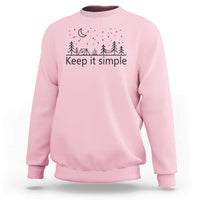 Light pink crewneck sweatshirt with “Keep it simple” forest and moon graphic
