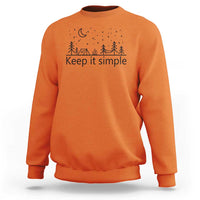 Orange crewneck sweatshirt with “Keep it simple” forest and moon graphic