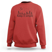Red crewneck sweatshirt with “Keep it simple” forest and moon graphic