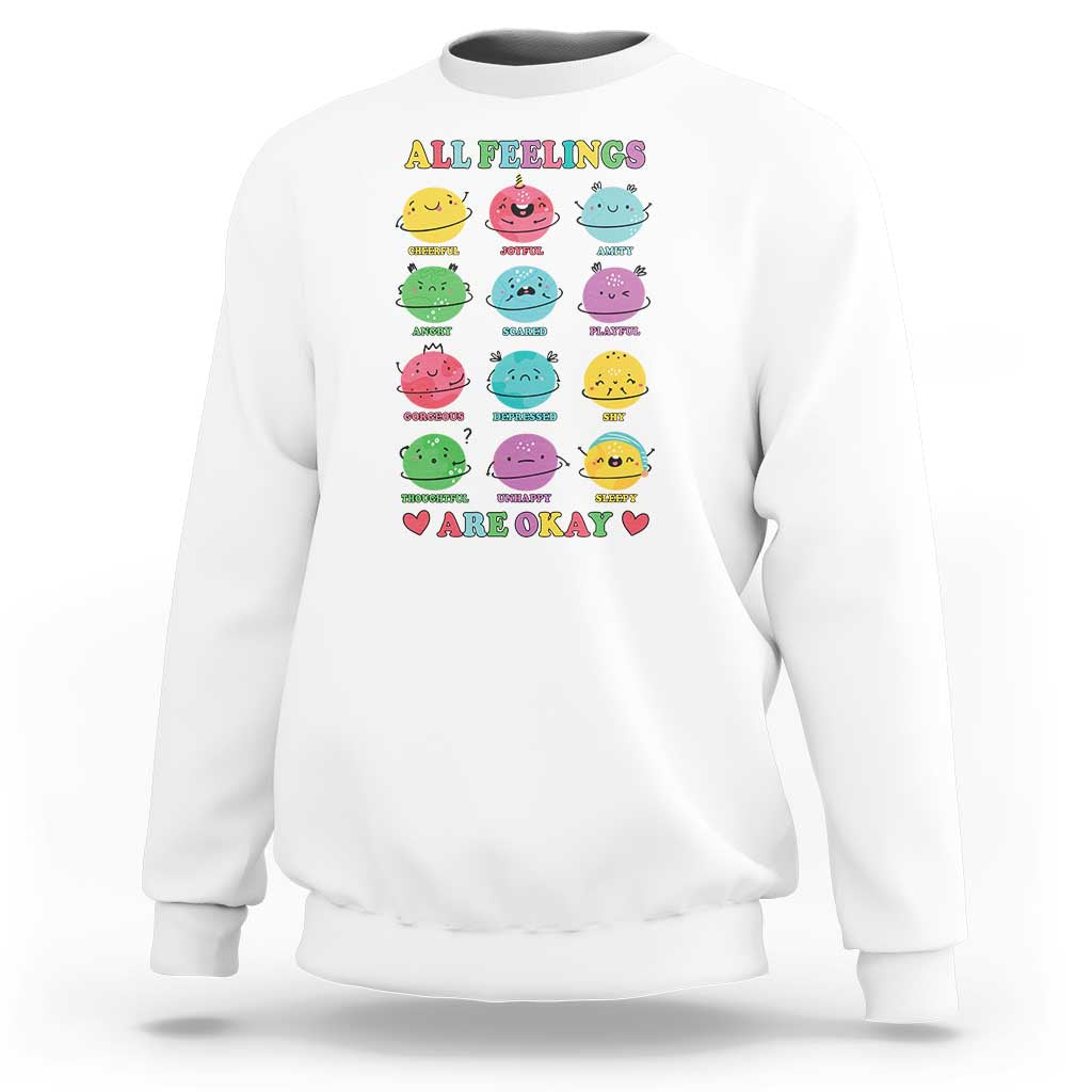 White sweatshirt with front graphic of colorful characters and 'All Feelings Are Okay' text