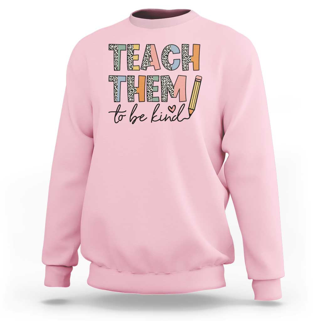Light pink teacher sweatshirt with “Teach Them” and “to be kind” pencil graphic.