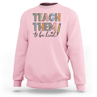 Light pink teacher sweatshirt with “Teach Them” and “to be kind” pencil graphic.