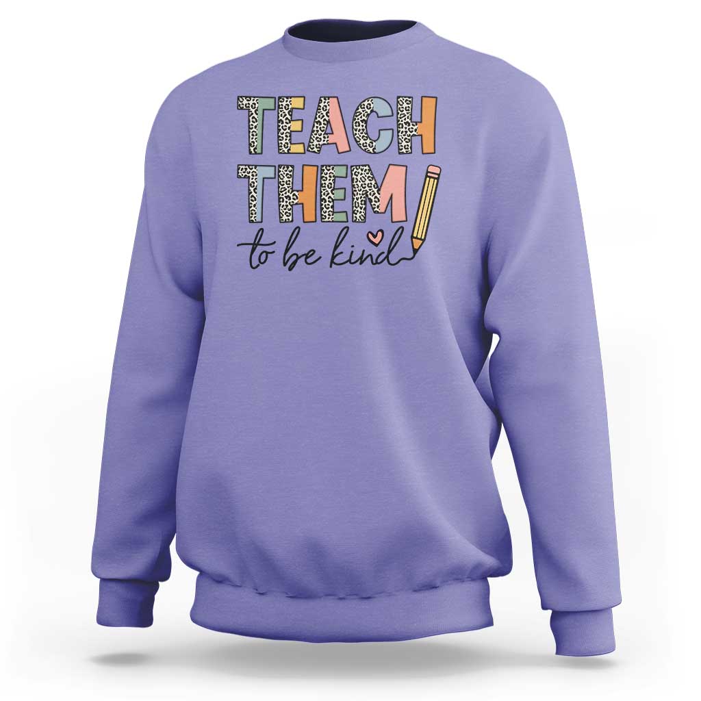 Violet teacher sweatshirt with “Teach Them” and “to be kind” pencil-style print.