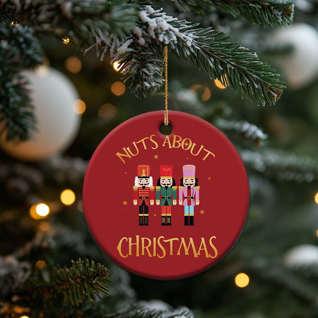 Red round “Nuts About Christmas” ornament with three nutcracker figures hanging on a tree