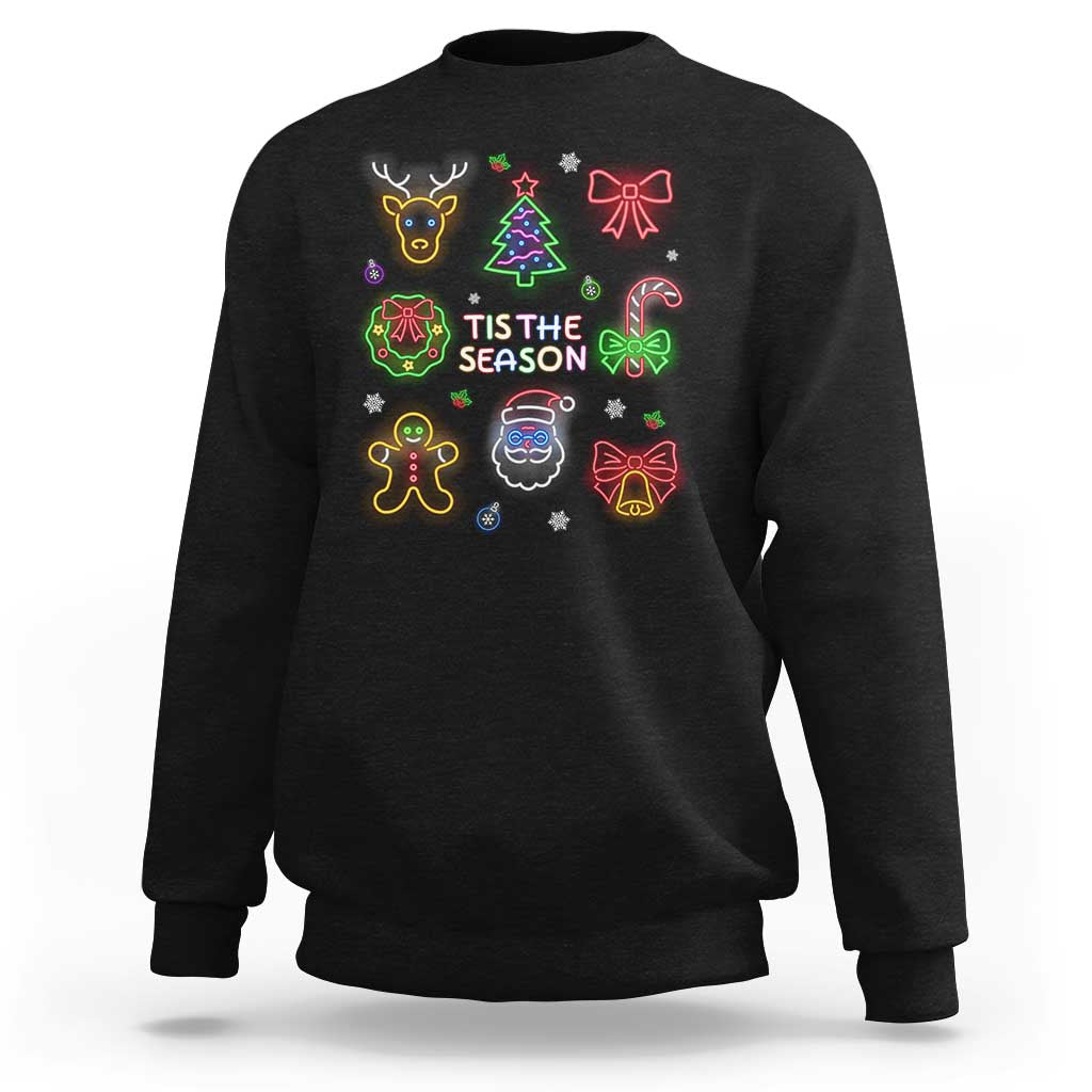Black unisex Christmas sweatshirt with neon holiday icons and 'TIS THE SEASON' print