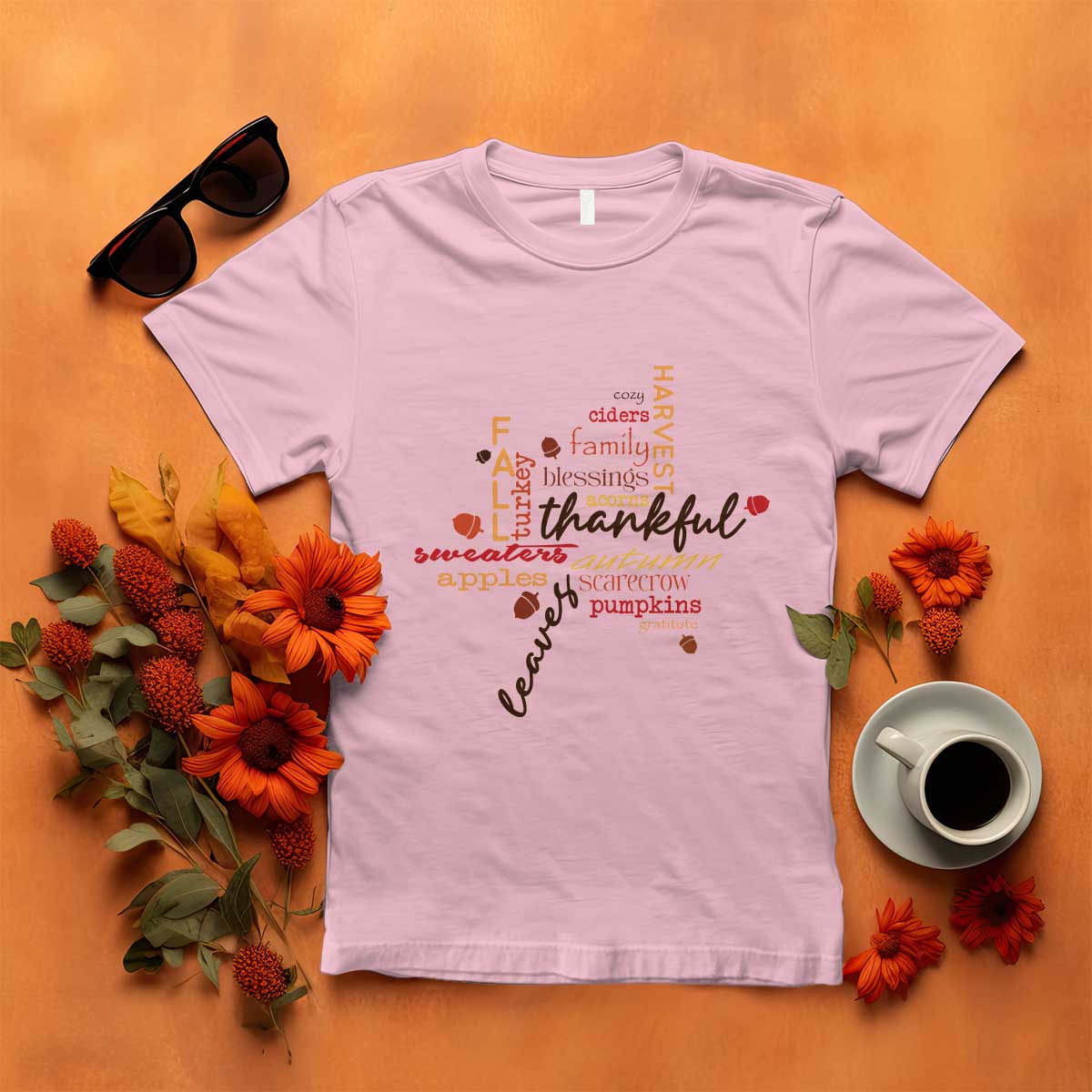 Light pink T-shirt with colorful "thankful" typography and autumn maple leaf graphic