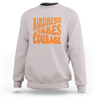 Light pink sweatshirt with orange 'Kindness Takes Courage' graphic on front.