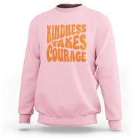 Light pink sweatshirt with orange 'Kindness Takes Courage' graphic on front.