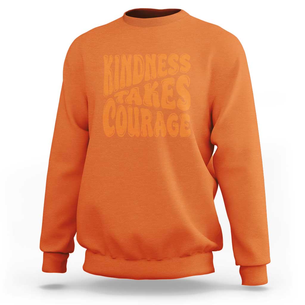 Orange sweatshirt with orange 'Kindness Takes Courage' graphic on front.