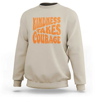 Sand sweatshirt with orange 'Kindness Takes Courage' graphic on front.