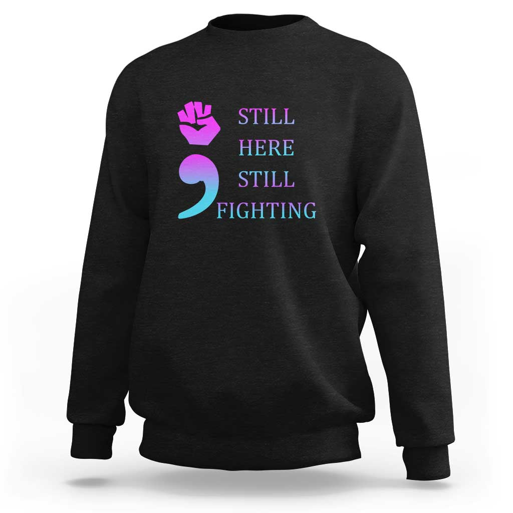 Black crewneck sweatshirt with “STILL HERE STILL FIGHTING” graphic and semicolon symbol