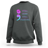 Charcoal crewneck sweatshirt with “STILL HERE STILL FIGHTING” graphic and semicolon symbol