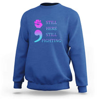Royal blue crewneck sweatshirt with “STILL HERE STILL FIGHTING” graphic and semicolon symbol