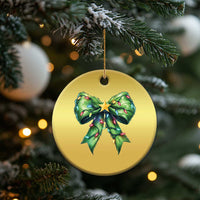 Round gold Christmas ornament with green bow and gold star, suspended from a gold cord.