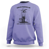 Purple sweatshirt with cowboy raccoon graphic and "God is testing me" text