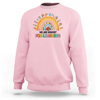 Light pink crewneck sweatshirt with rainbow and “We are hungry for learning” graphic