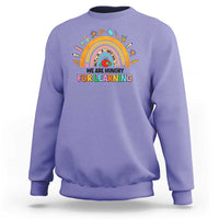 Violet crewneck sweatshirt with rainbow and “We are hungry for learning” graphic