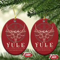 Pair of red oval Christmas ornaments with gold hanging strings and antlered skull emblem.