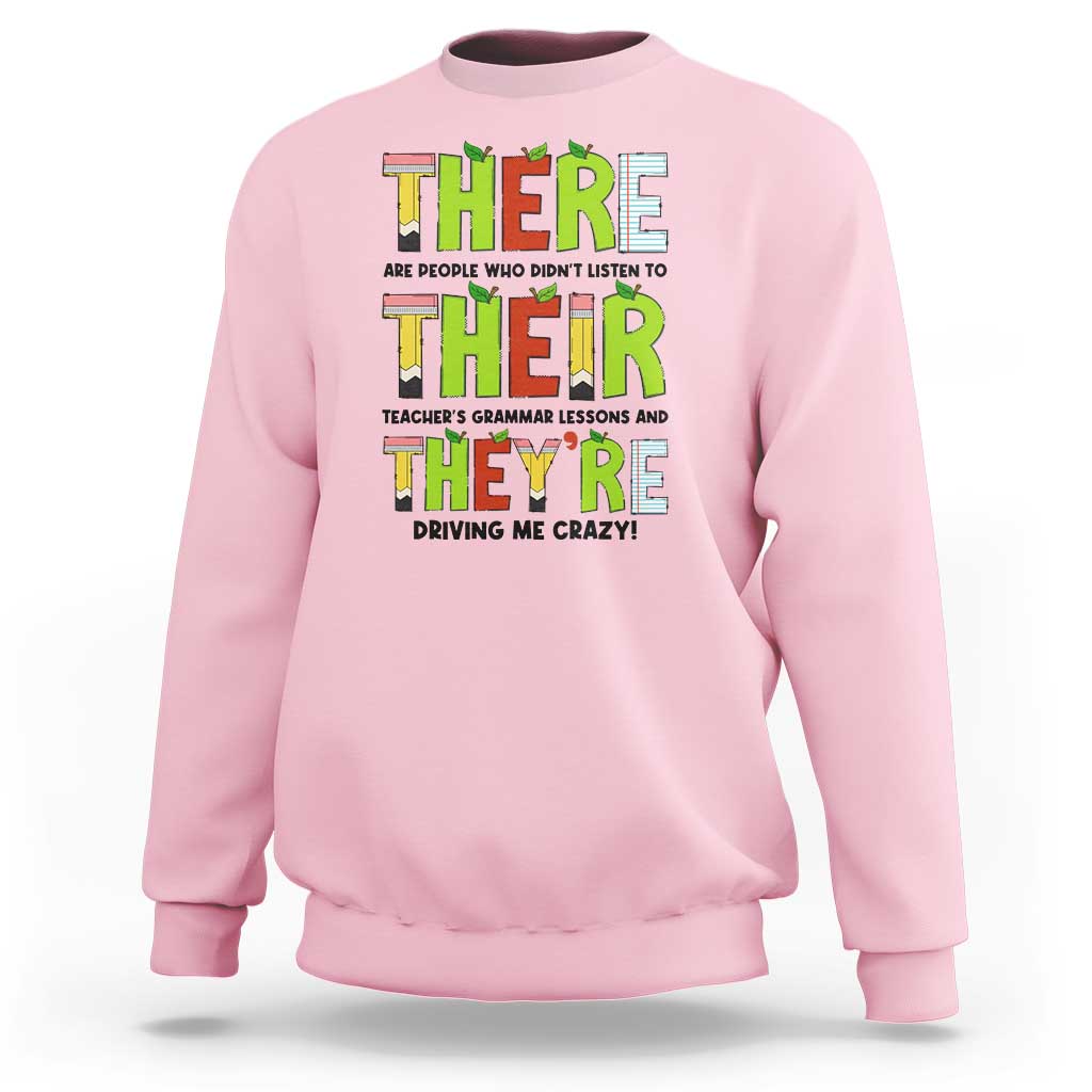Pink sweatshirt with colorful “THERE/THEY’ grammar text graphic on the front