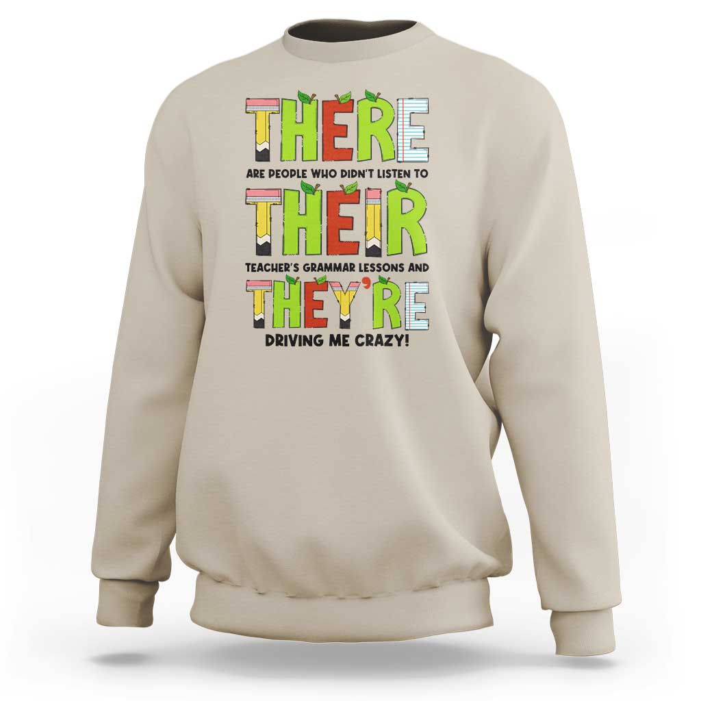 Sand/beige sweatshirt with colorful “THERE/THEY’ grammar text graphic on the front, crew neck